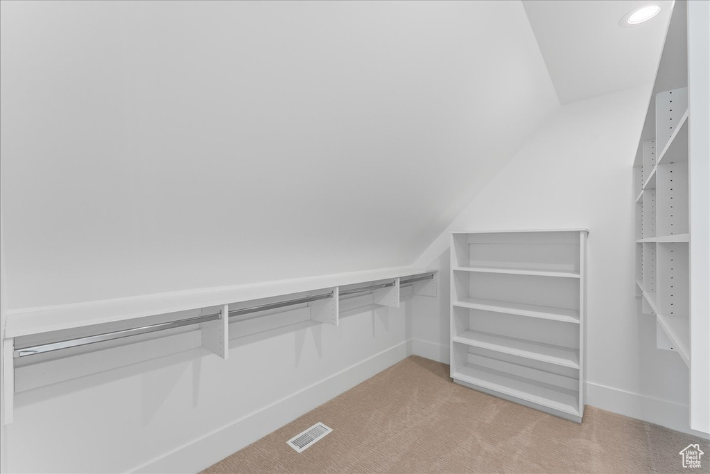 Spacious closet with light colored carpet and vaulted ceiling