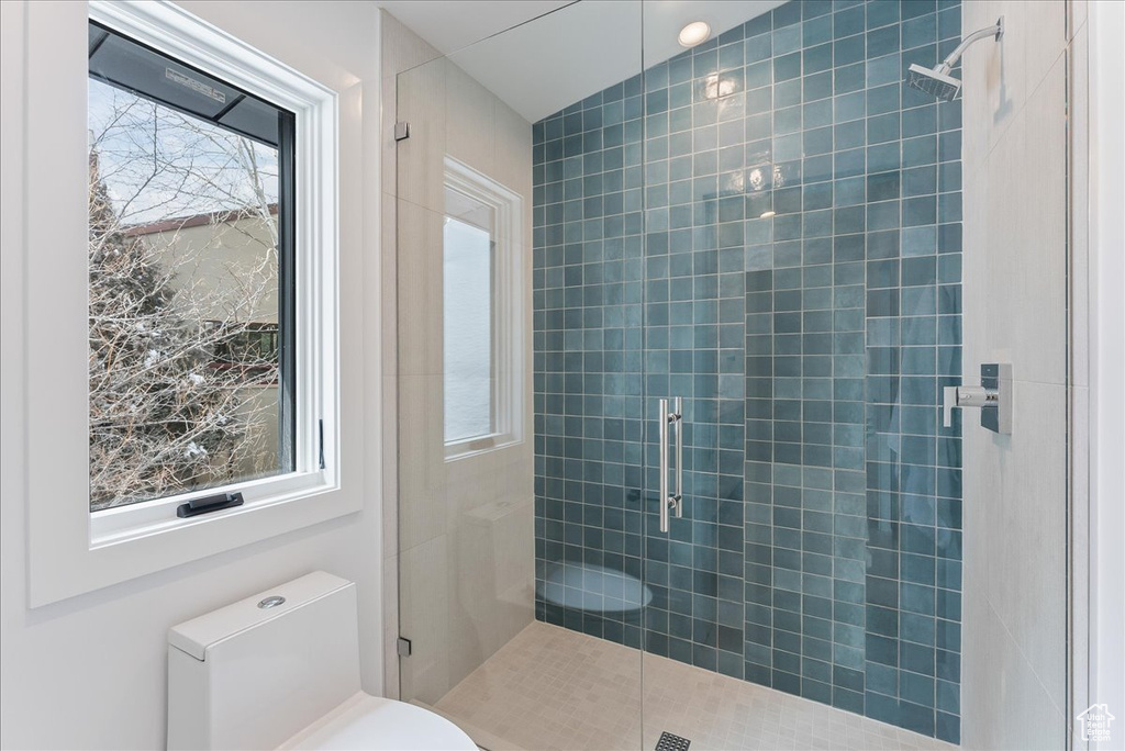 Bathroom featuring walk in shower, toilet, and a wealth of natural light