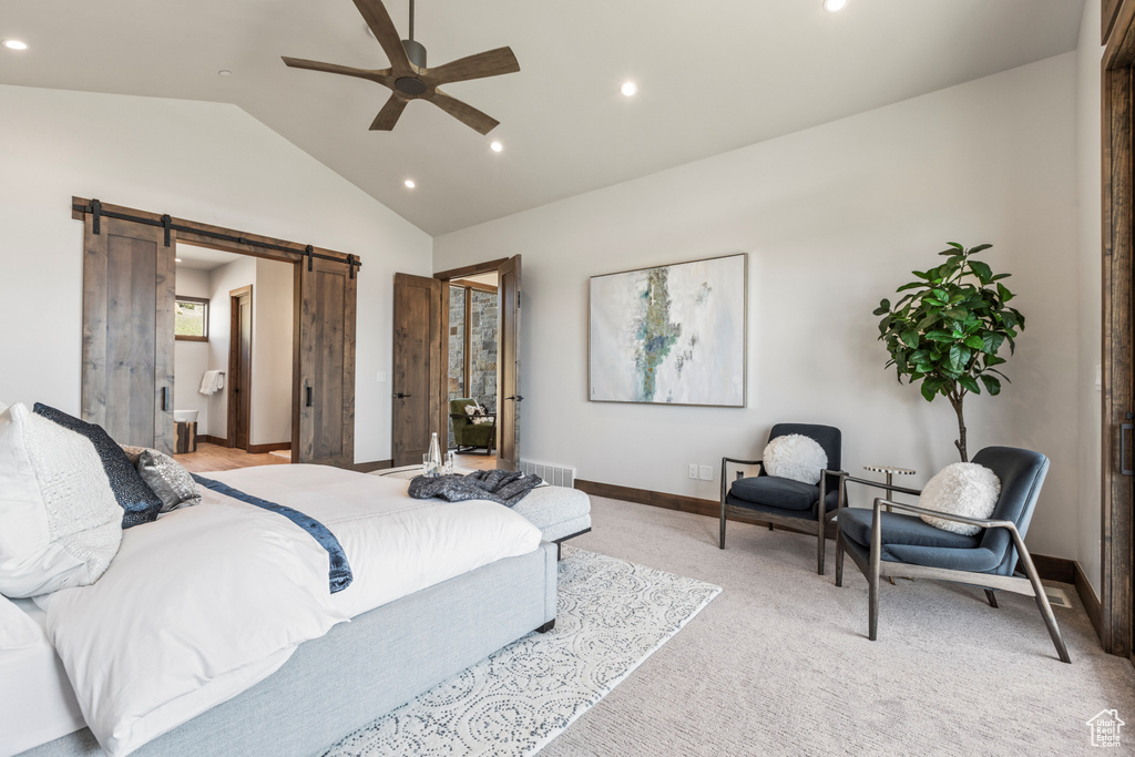 Carpeted bedroom with a barn door, ensuite bathroom, ceiling fan, and lofted ceiling