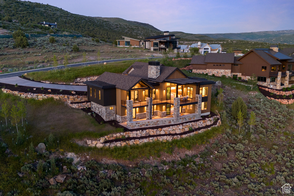 Back house at dusk featuring a mountain view and a balcony