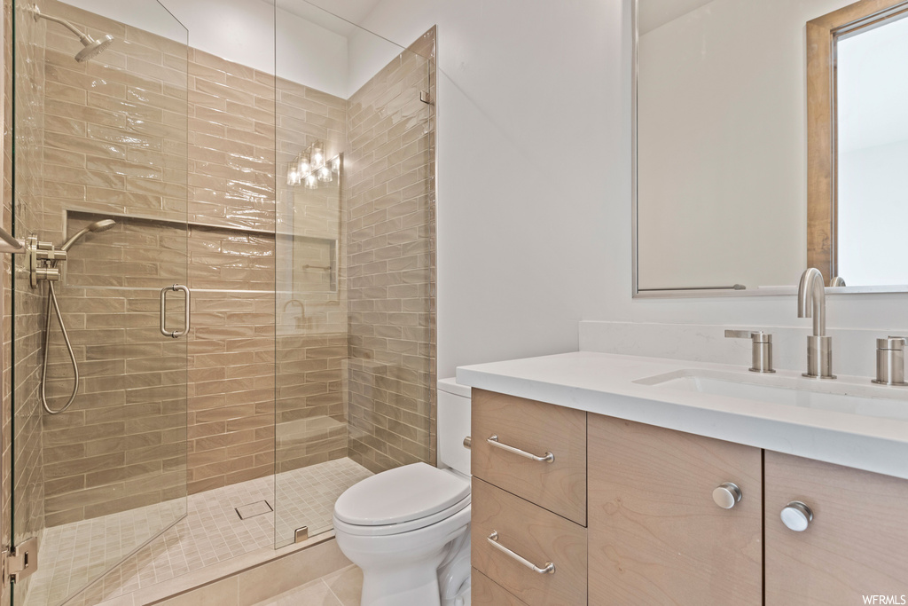 Bathroom with an enclosed shower, toilet, large vanity, and tile flooring