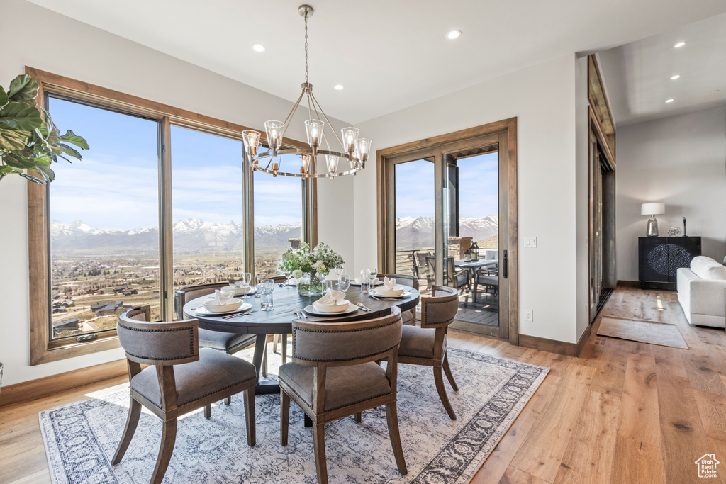 Dining area with light hardwood / wood-style flooring, a mountain view, and a notable chandelier
