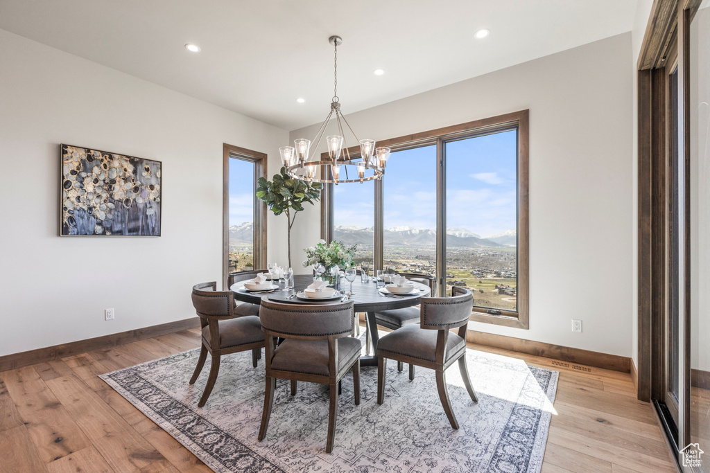 Dining space with a mountain view, light hardwood / wood-style flooring, and a chandelier