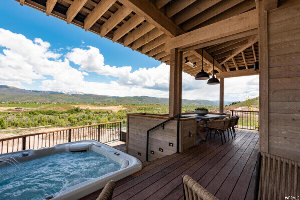 Deck with an outdoor hot tub and a mountain view