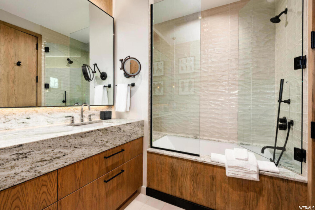 Bathroom with shower / bath combination with glass door, large vanity, and tile floors
