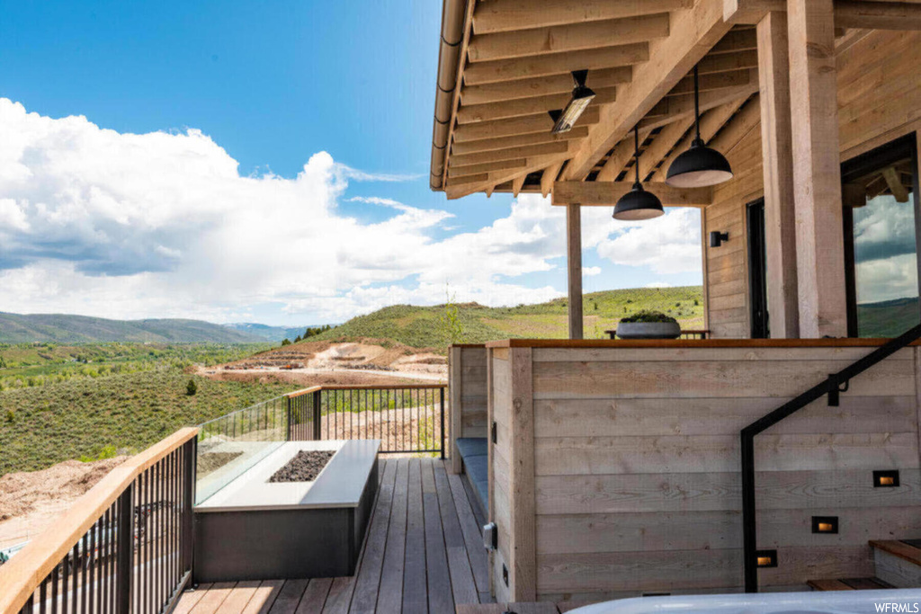 Wooden deck featuring an outdoor fire pit and a mountain view