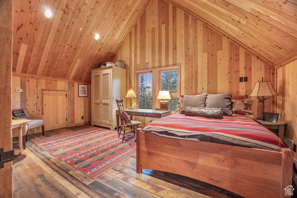 Bedroom with hardwood / wood-style floors, wooden walls, high vaulted ceiling, and wood ceiling