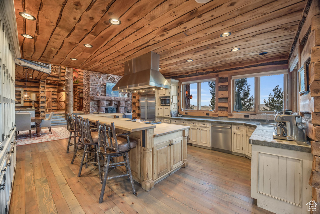 Kitchen with log walls, a center island, island range hood, wooden ceiling, and light hardwood / wood-style flooring