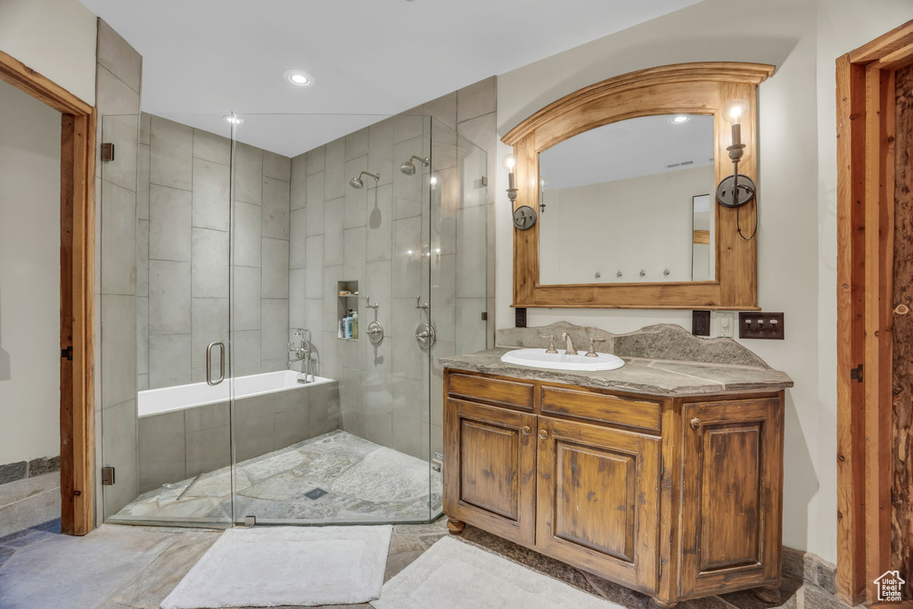 Bathroom with vanity with extensive cabinet space, shower with separate bathtub, and tile floors
