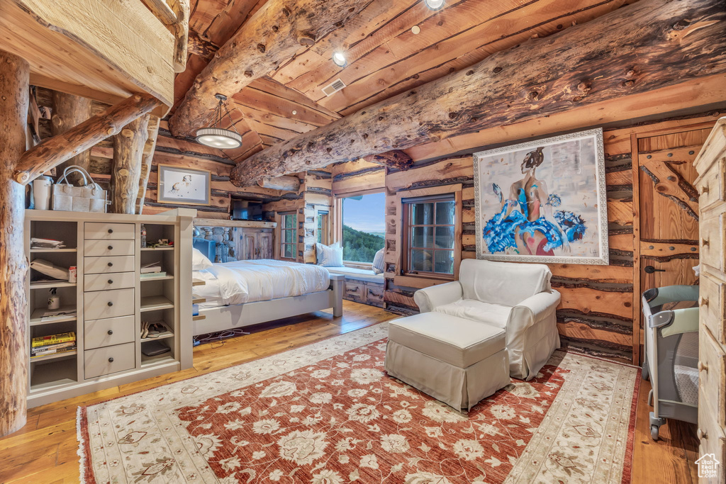 Bedroom with beamed ceiling, wood ceiling, light hardwood / wood-style floors, and rustic walls