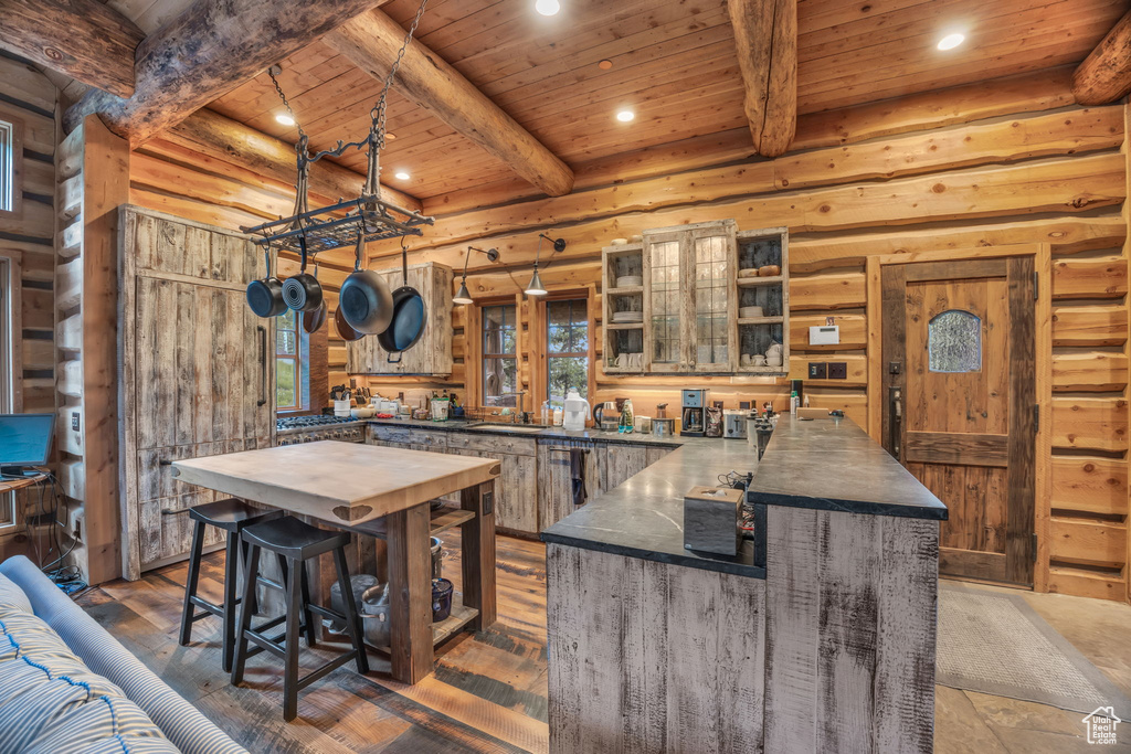 Kitchen featuring beamed ceiling, wood ceiling, dark hardwood / wood-style flooring, and rustic walls