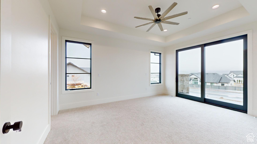 Carpeted empty room with plenty of natural light and a tray ceiling