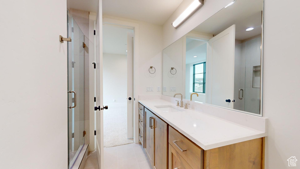 Bathroom with tile floors, a shower with shower door, and vanity with extensive cabinet space