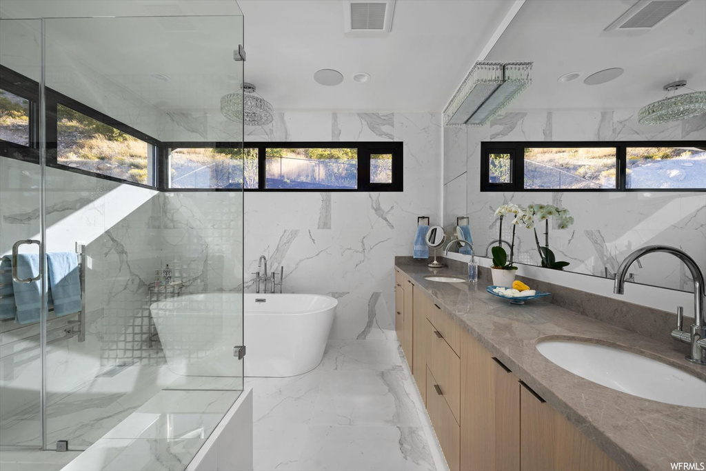 Bathroom featuring tile flooring, a healthy amount of sunlight, tile walls, and dual bowl vanity