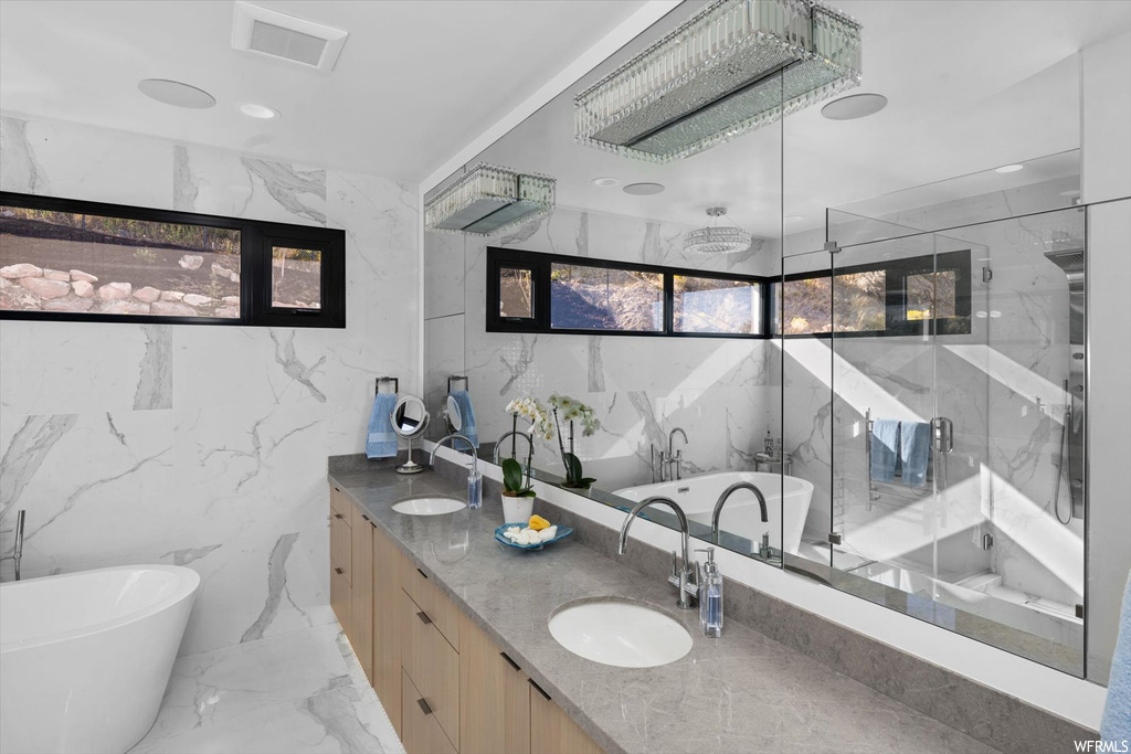 Bathroom featuring tile floors, tile walls, double vanity, and plus walk in shower