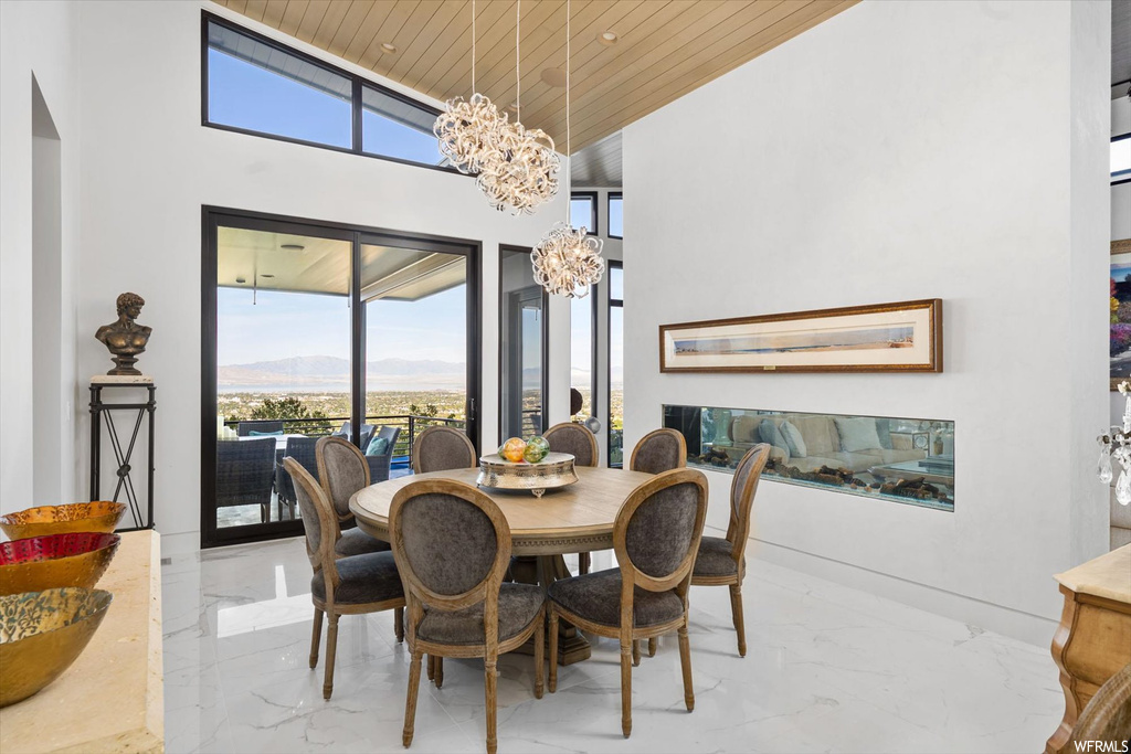 Dining space featuring wood ceiling, light tile floors, a high ceiling, a notable chandelier, and a mountain view