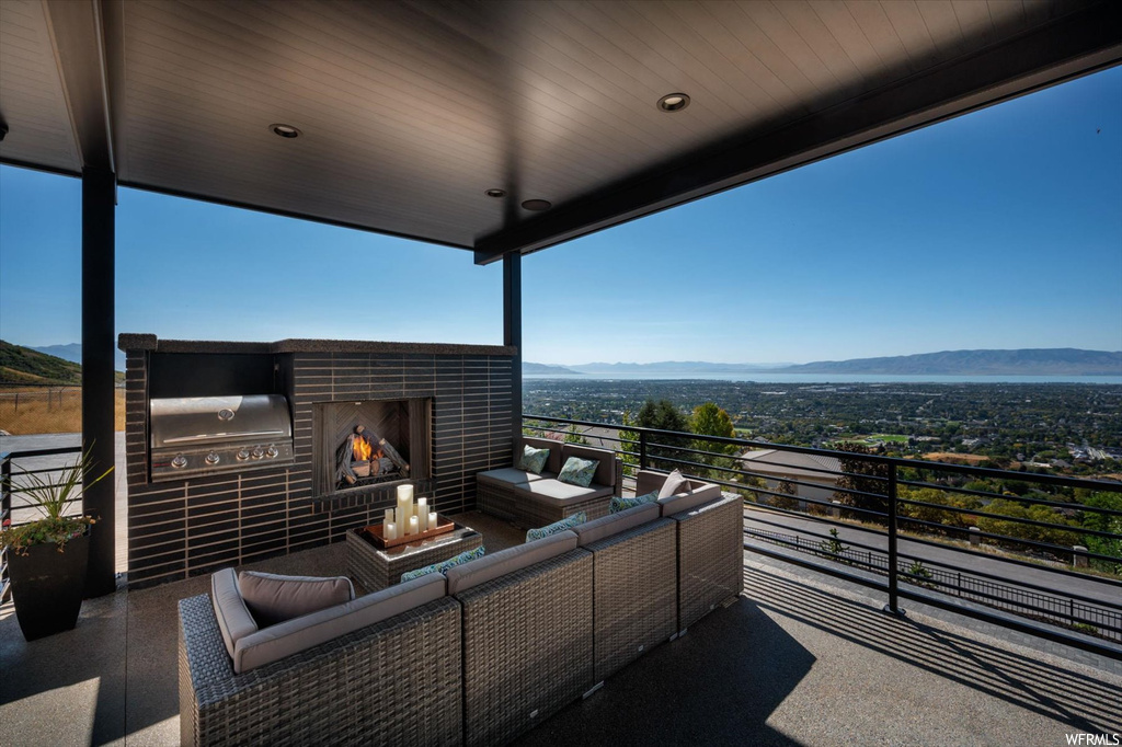 View of patio featuring an outdoor living space with a fireplace, a balcony, a mountain view, and grilling area