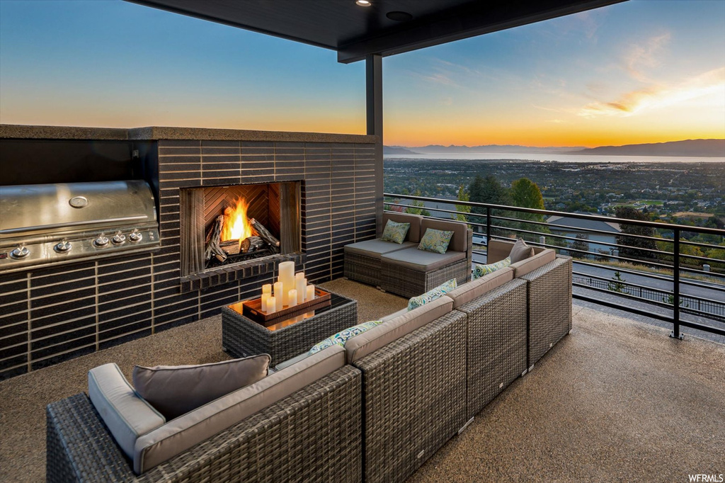 Patio terrace at dusk with a balcony and a fireplace