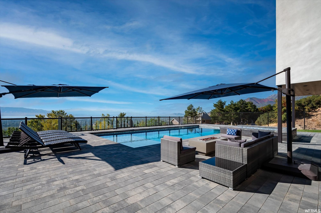 View of pool with an outdoor living space with a fire pit