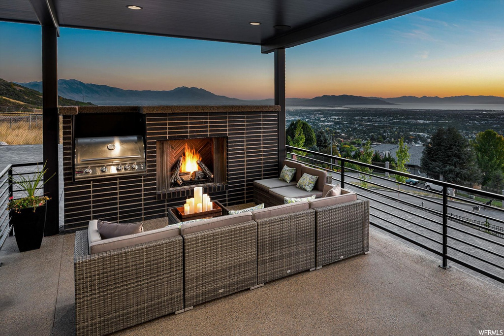 Balcony at dusk featuring a mountain view, a fireplace, and grilling area