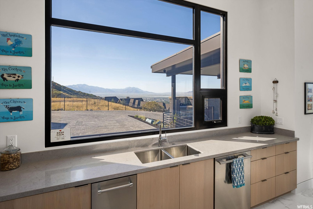 Kitchen with stainless steel dishwasher, light brown cabinets, light tile flooring, dark stone counters, and a mountain view