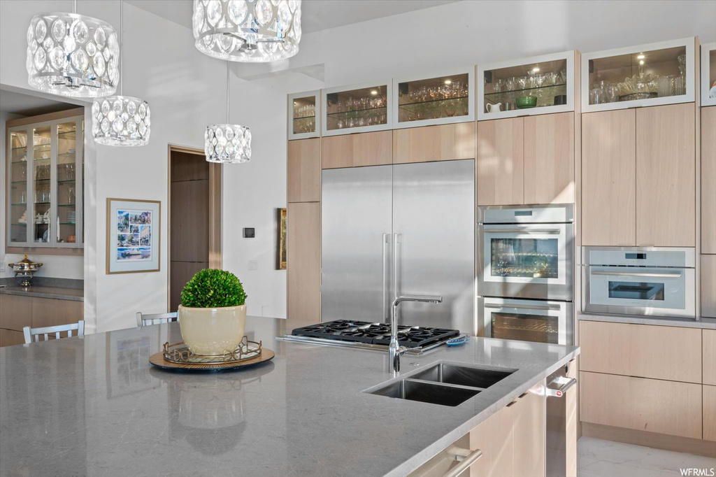 Kitchen featuring pendant lighting, light brown cabinets, an inviting chandelier, and appliances with stainless steel finishes