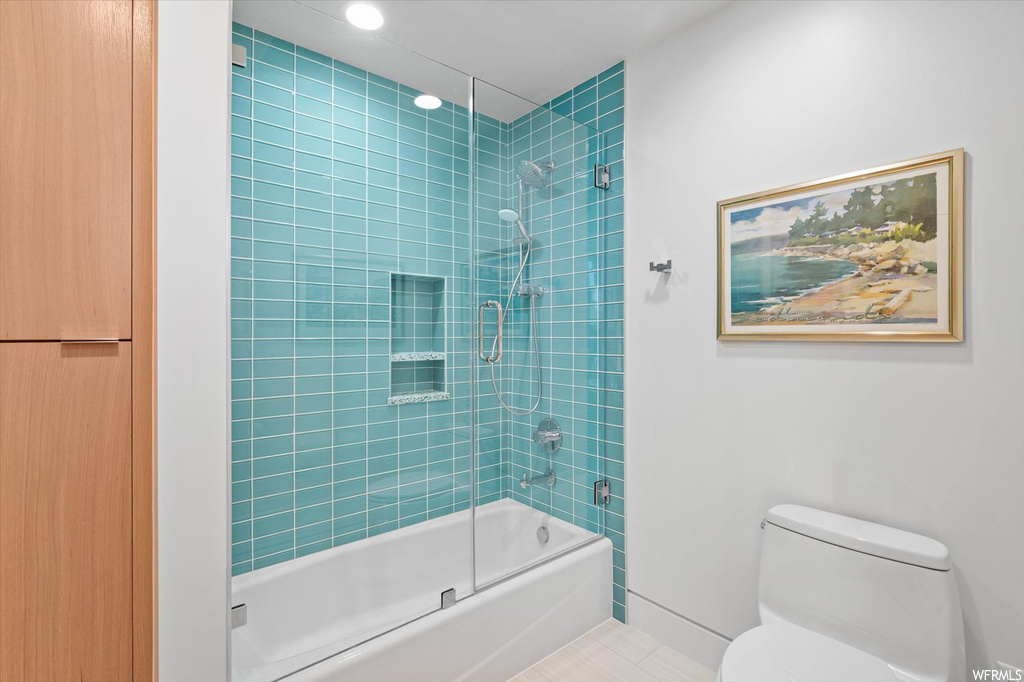Bathroom featuring bath / shower combo with glass door, tile flooring, and toilet