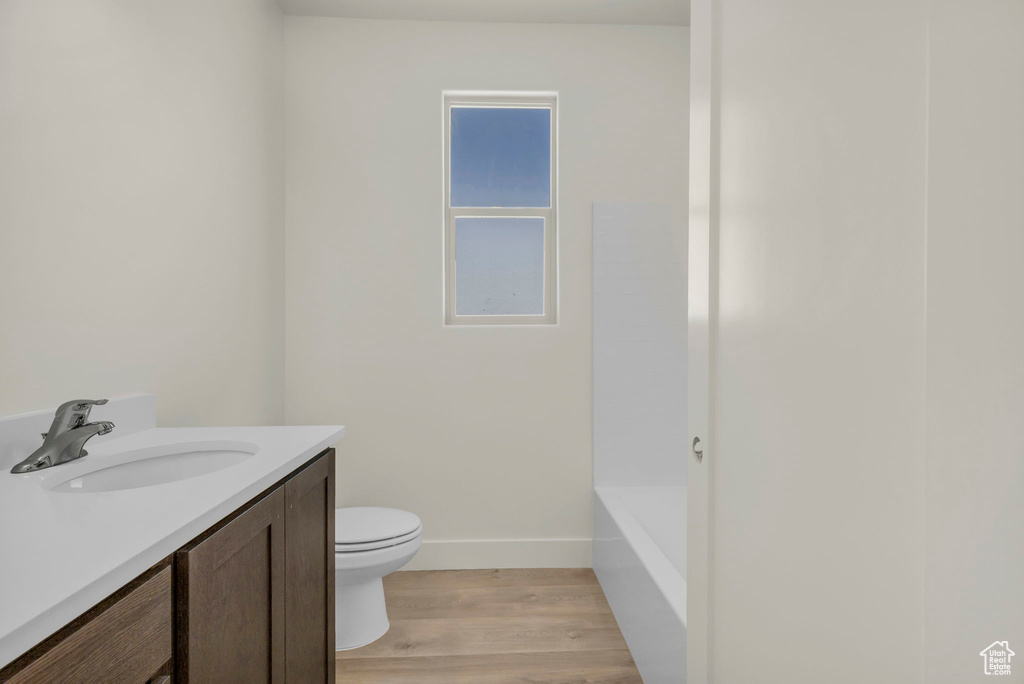 Full bathroom with vanity, toilet, tub / shower combination, and wood-type flooring