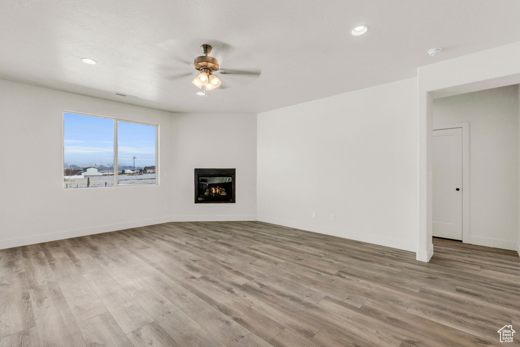 Unfurnished living room with light wood-type flooring and ceiling fan