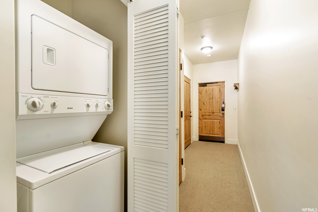 Laundry room with light carpet and stacked washer / drying machine