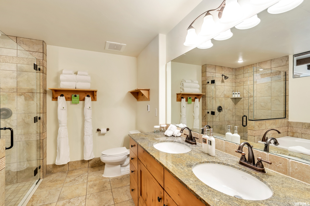 Full bathroom featuring tile flooring, separate shower and tub, dual bowl vanity, and toilet