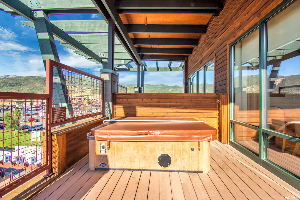 Wooden terrace featuring a hot tub and a mountain view
