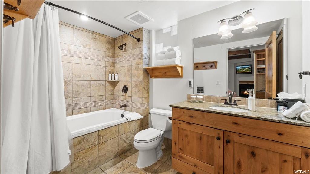 Full bathroom with tile flooring, toilet, vanity, and shower / bath combo with shower curtain