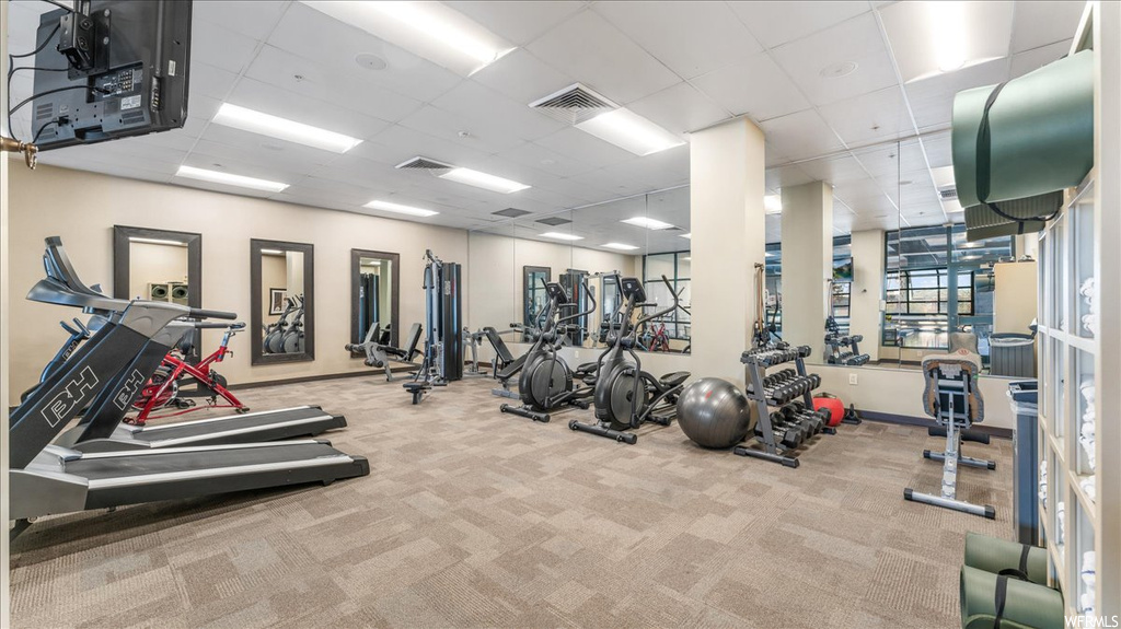Workout area featuring light colored carpet and a drop ceiling
