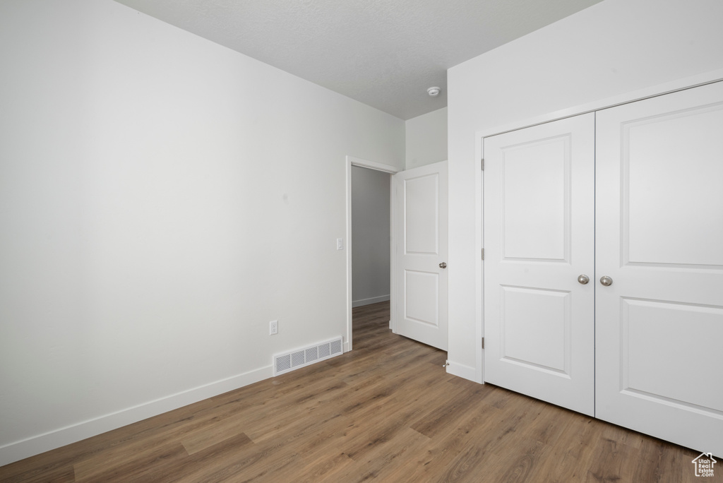 Unfurnished bedroom featuring hardwood / wood-style floors and a closet