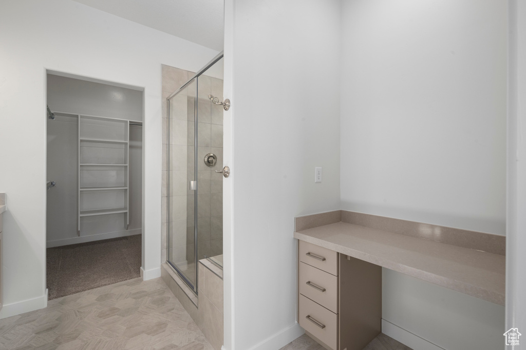 Bathroom with tile flooring, a shower with shower door, and vanity