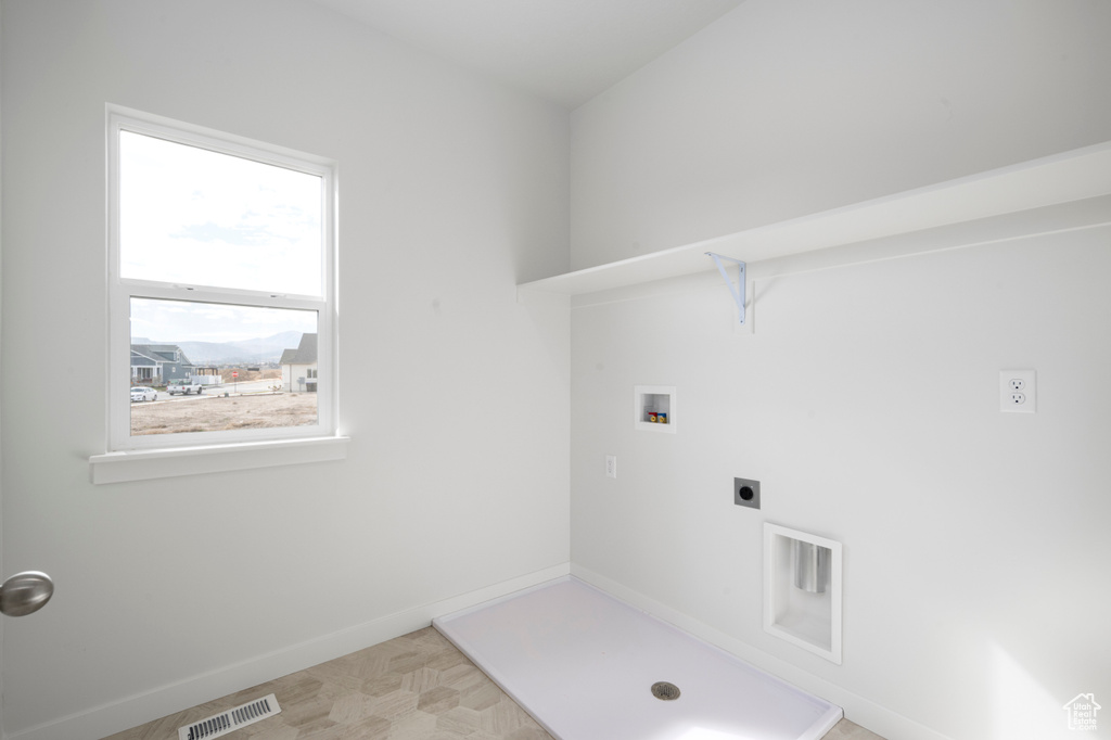 Clothes washing area featuring a wealth of natural light, hookup for an electric dryer, light tile floors, and hookup for a washing machine