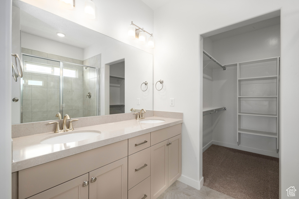 Bathroom with a shower with door, dual sinks, and oversized vanity