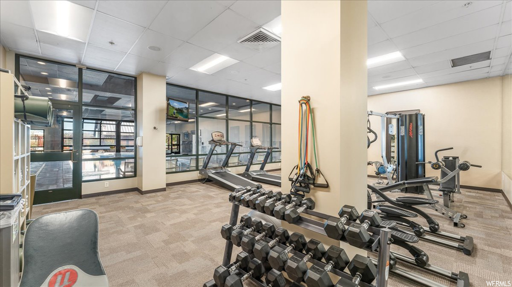 Exercise room with light colored carpet and a drop ceiling