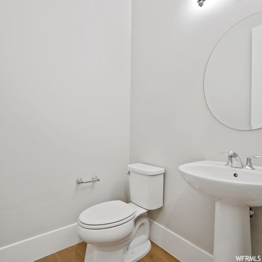 Bathroom featuring sink, toilet, and wood-type flooring