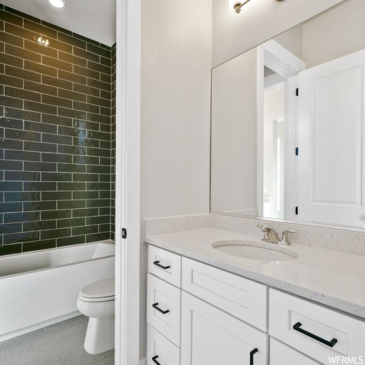Full bathroom featuring tile floors, large vanity, toilet, and tiled shower / bath