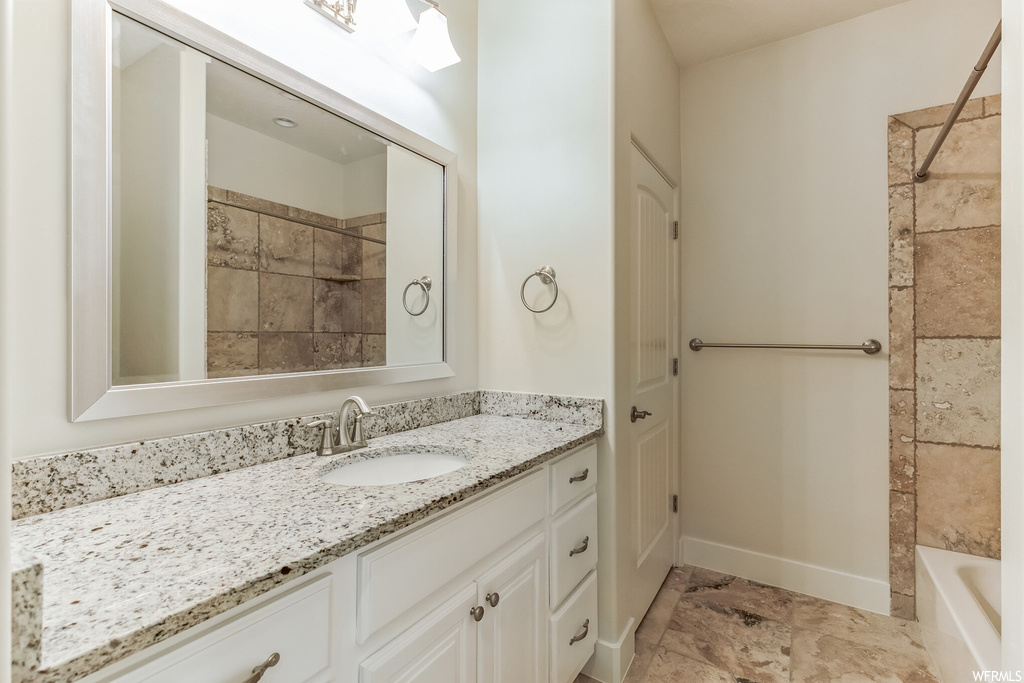 Bathroom with tile floors, vanity with extensive cabinet space, and tiled shower / bath combo
