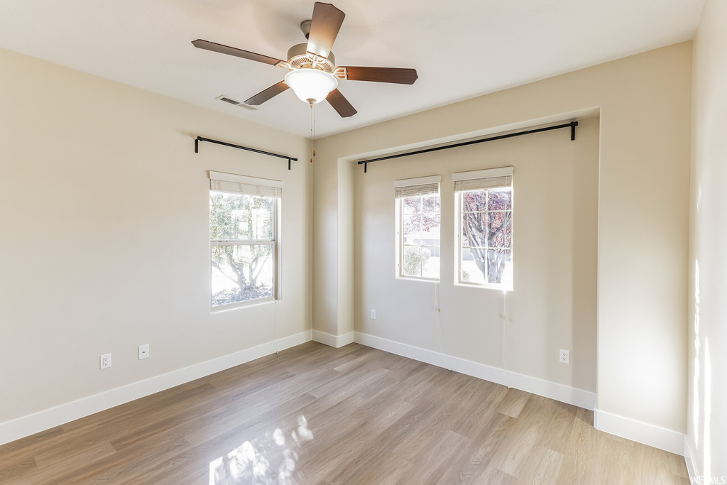 Unfurnished bedroom featuring multiple windows, ceiling fan, a closet, and light hardwood flooring