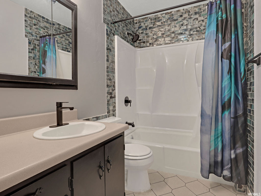 Full bathroom featuring shower / bath combination with curtain, vanity, tile floors, and toilet