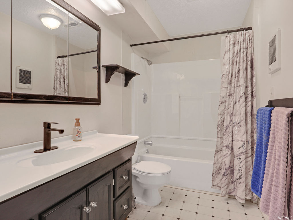 Full bathroom with large vanity, shower / tub combo with curtain, toilet, and tile flooring