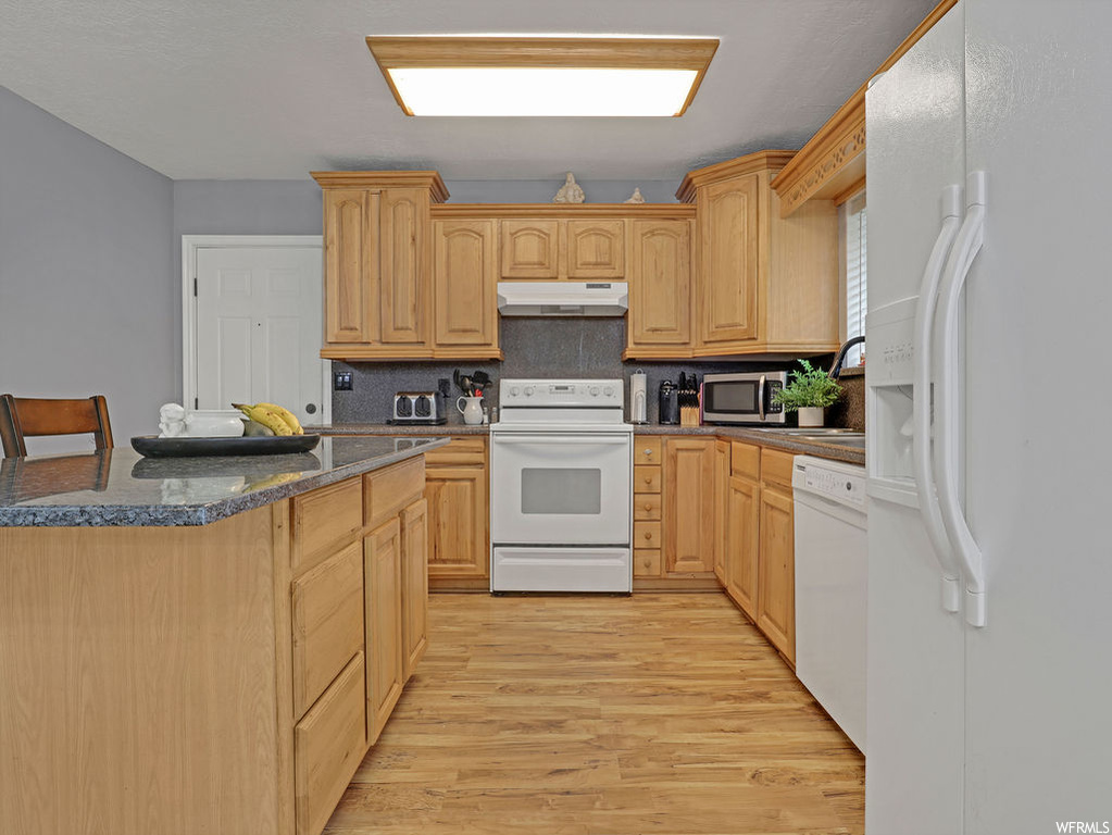 Kitchen featuring backsplash, white appliances, light hardwood floors, and light brown cabinetry