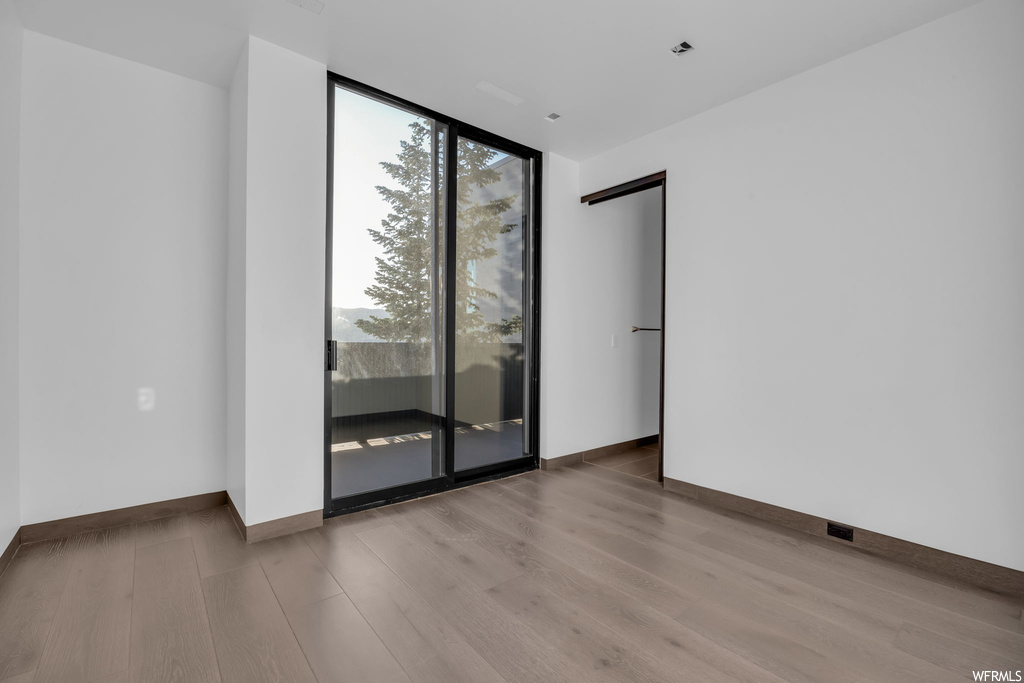 Hardwood floored spare room featuring expansive windows