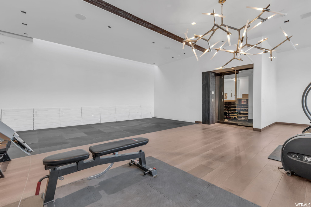 Workout area with an inviting chandelier and light hardwood floors