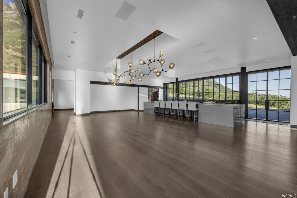 Unfurnished room featuring dark hardwood flooring and a notable chandelier
