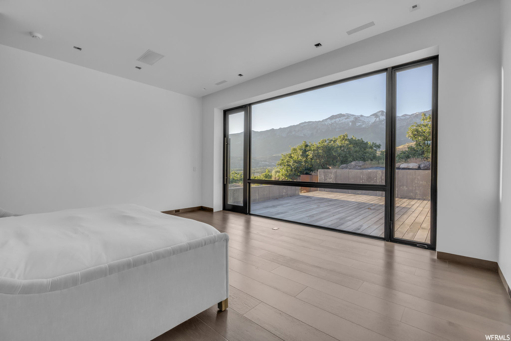 Bedroom with a mountain view, hardwood floors, and access to outside
